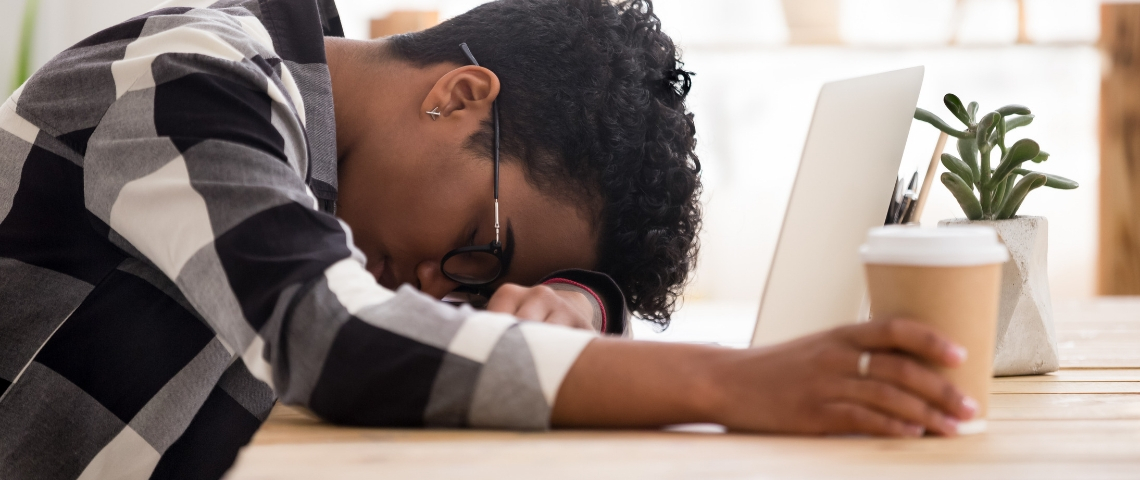 Pourquoi sommes-nous fatigués au travail ? une femme en train de dormir devant son ordinateur