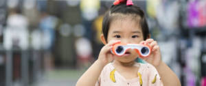Une petite fille chinoise qui tient des jumelles dans les mains