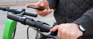 Un homme paye une trottinette électrique avec son smartphone.