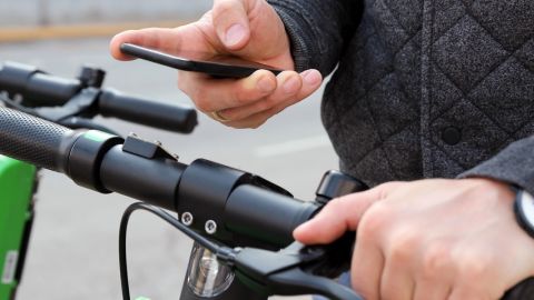 Un homme paye une trottinette électrique avec son smartphone.