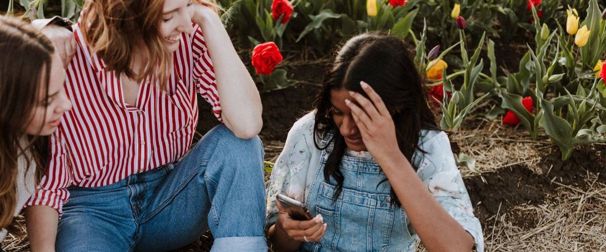 Visibrain lance son module de veille dédié aux tendances Instagram Trois jeunes femmes se prennent en photo sur un smartphone. Au milieu d'un champ de tulipes.