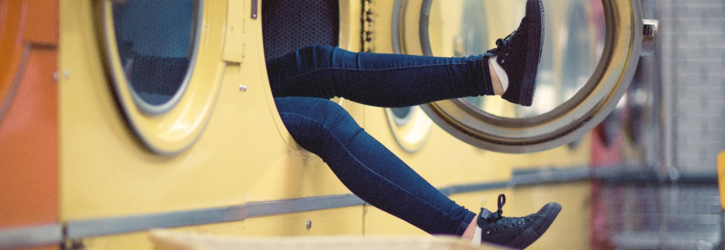 À quelle fréquence faut-il laver ses vêtements tous les jours ? Des jambes qui sortent d'une machine à laver dans une laverie
