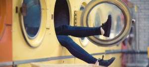 Des jambes qui sortent d'une machine à laver dans une laverie