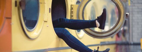 À quelle fréquence faut-il laver ses vêtements tous les jours ? Des jambes qui sortent d'une machine à laver dans une laverie