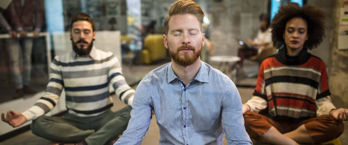 Comment améliorer son expérience collaborateur ? Trois personnes qui font du yoga au burea