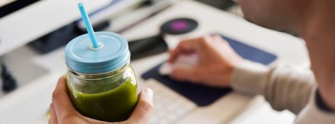 Comment être plus écolo au bureau ? Un employé de bureau boit un smoothie vert