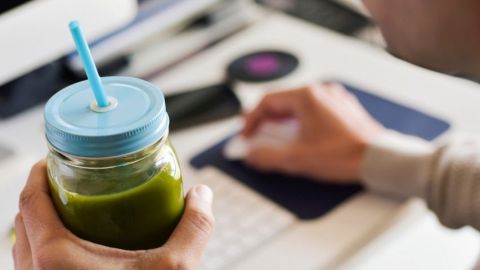 Un employé de bureau boit un smoothie vert