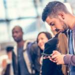 Jeune homme regarde avec anxiété son téléphone à l'aéroport