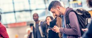 Jeune homme regarde avec anxiété son téléphone à l'aéroport