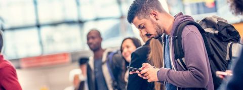 La Chine installe un logiciel espion sur le smartphone des touristes Jeune homme regarde avec anxiété son téléphone à l'aéroport