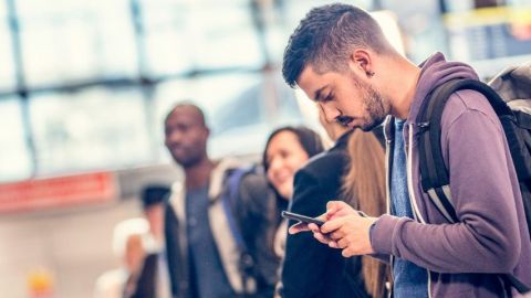 Jeune homme regarde avec anxiété son téléphone à l'aéroport