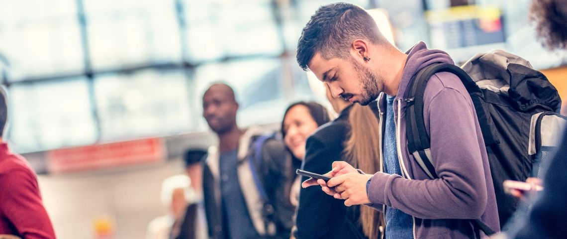 La Chine installe un logiciel espion sur le smartphone des touristes Jeune homme regarde avec anxiété son téléphone à l'aéroport