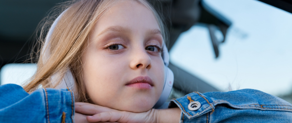 Pour avoir la paix en voiture, les podcast sont fantastiques Une petite fille avec un casque audio sur les oreilles