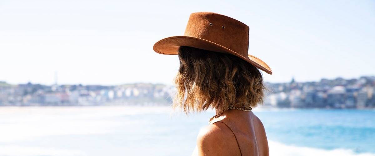 Les influenceurs connaissent une baisse d'engagement jamais connu Une femme porte un chapeau de dos face à la plage