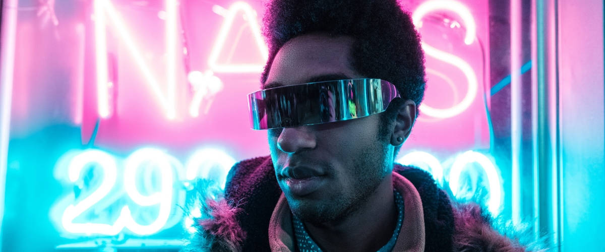 Comment utiliser les objets connectés pour son marketing par l'objet ? Un homme noir avec des lunettes devant des néons