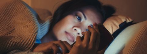 Les ados vivent leur vie numérique dans leur lit une jeune fille asiatique regarde un smartphone allongée dan un lit