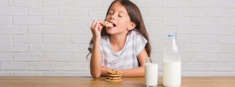 Le lobby du lait infiltre les écoles Un jeune enfant aux cheveux longs en train de manger un cookie trempé dans un verre de lait