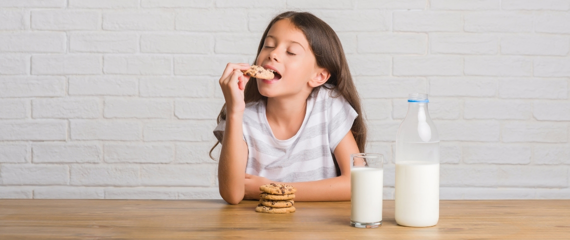 Le lobby du lait infiltre les écoles Un jeune enfant aux cheveux longs en train de manger un cookie trempé dans un verre de lait