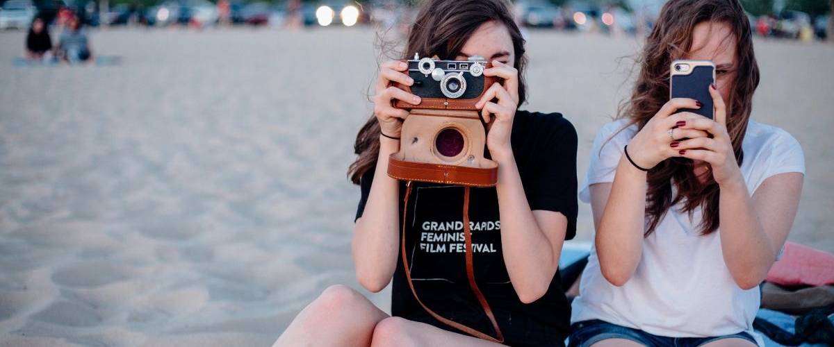 Les adolescent fuient Facebook pour le plus grand bonheur d'Instagram Deux jeunes adolescentes prennent des photos à la plage sur leur téléphone et un appareille photo