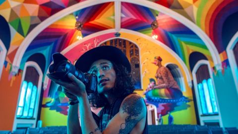 un homme tatoué prend une photo dans une église colorée