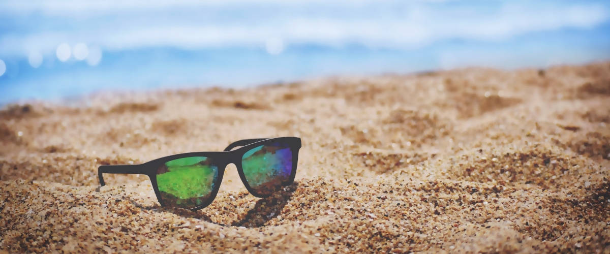 Les meilleures villes où draguer cet été Une paire de lunette de soleil sur le sable