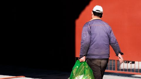 Un homme asiatique de dos tient un sac poubelle