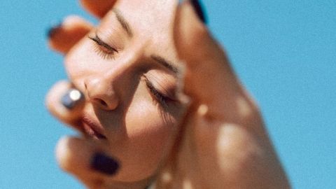 Une femme regarde son reflet dans un miroir brisé