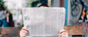 Personne lisant un journal sur un banc.