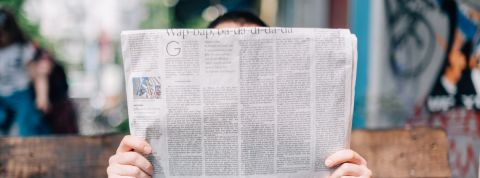 Les faux communiqués de presse, ce fléau qui coûte gros Personne lisant un journal sur un banc.