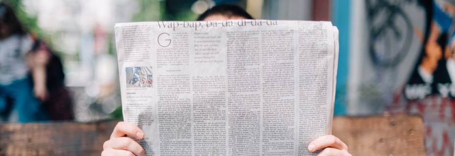 Personne lisant un journal sur un banc.