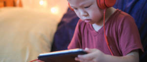 un petit garçon avec des gros écouteurs regarde un écran