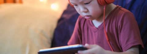 Youtube va rester ouvert à tous les contenus, même les plus controversés un petit garçon avec des gros écouteurs regarde un écran