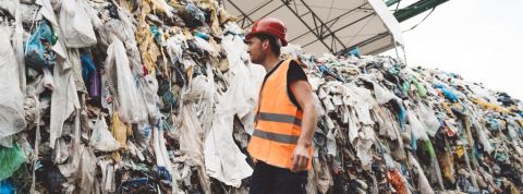 La Fashion Week pollue homme regardant un tas de dechets de vetements
