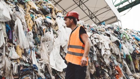 homme regardant un tas de dechets de vetements