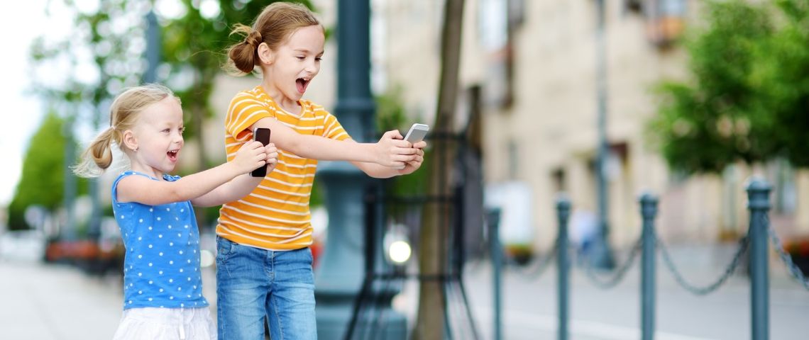 Comment créer une opération phygitale efficace ? Deux petites filles jouent avec un smartphone