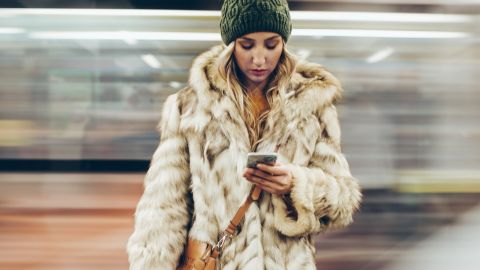 Une femme avec un manteau en fourrure sur le quai d'un métro