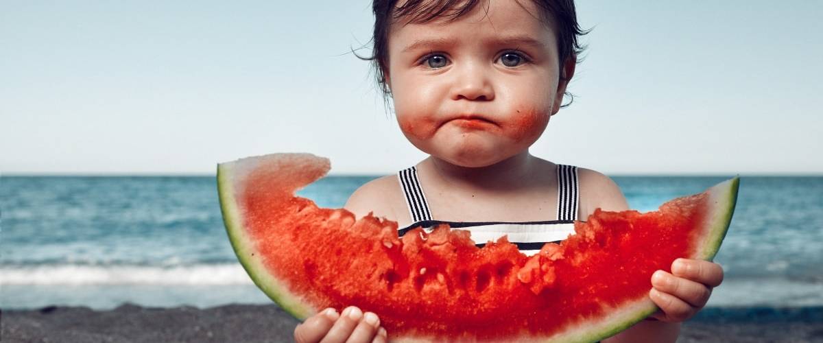 Les meilleures applications anti-gaspi Une petite fille à la plage en train de manger une pastèque