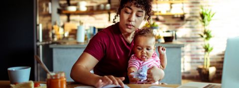 Où trouve-t-on le meilleur équilibre vie pro / vie perso ? Une femme travaillant sur son ordinateur avec un enfant dans les bras