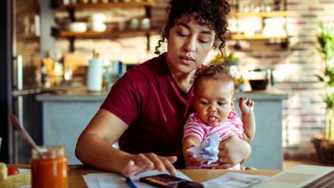 Une femme travaillant sur son ordinateur avec un enfant dans les bras