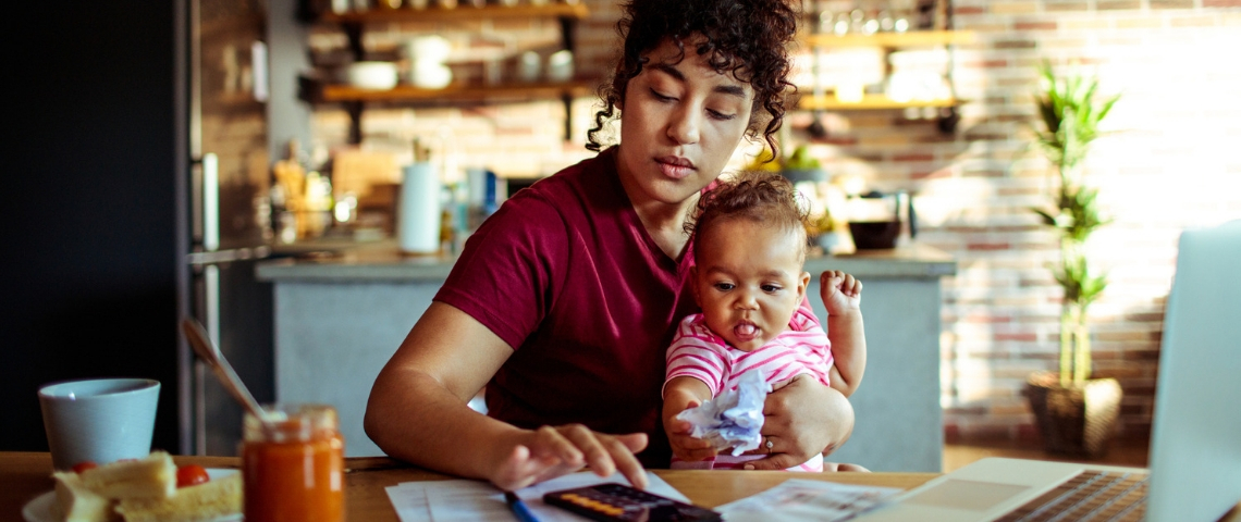 Où trouve-t-on le meilleur équilibre vie pro / vie perso ? Une femme travaillant sur son ordinateur avec un enfant dans les bras