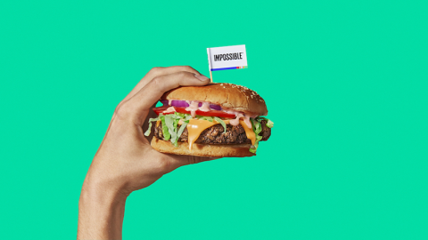 Une main qui tient un hamburger sur un fond vert