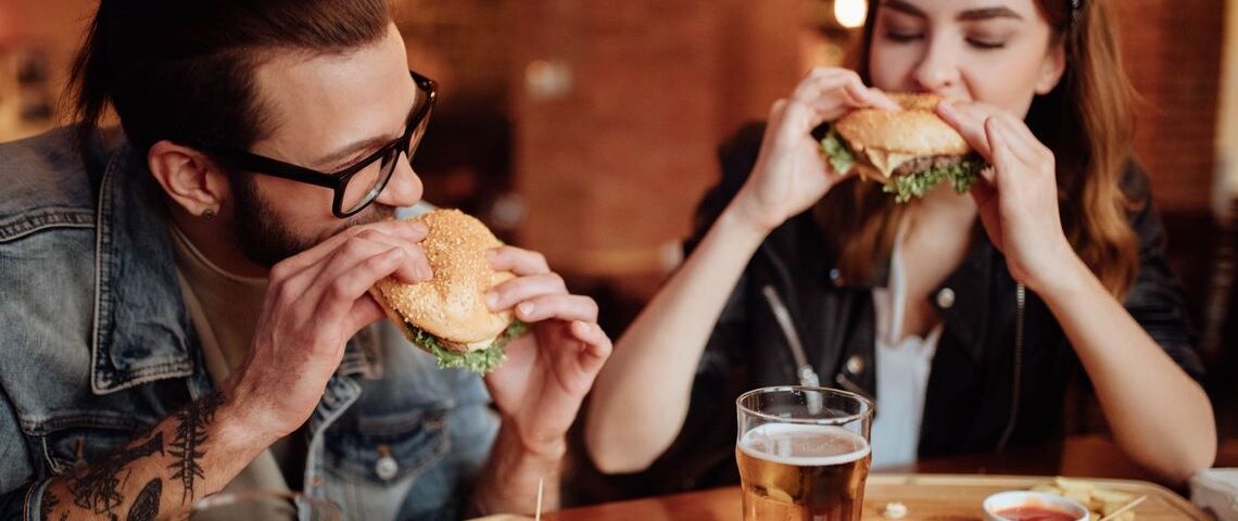 Où manger zéro déchet ? Un homme et une femme qui mangent des burgers