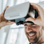 Un homme souriant met un casque de réalité virtuelle.