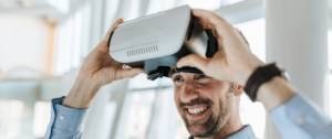 Un homme souriant met un casque de réalité virtuelle.