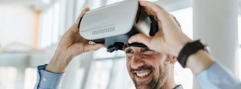 Être une entreprise - tech - devient ringard Un homme souriant met un casque de réalité virtuelle.