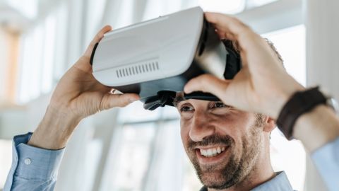 Un homme souriant met un casque de réalité virtuelle.