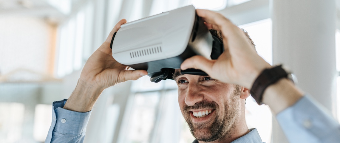 Être une entreprise Un homme souriant met un casque de réalité virtuelle.