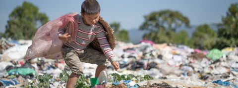 Où vont vraiment nos déchets plastique ? Un petit garçon en train de ramasser des déchets dans une décharge plastique à ciel ouvert