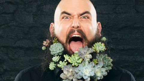 Un homme barbu envahi de plantes vertes