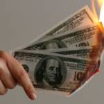 Une main qui tient des billets de dollars en feu